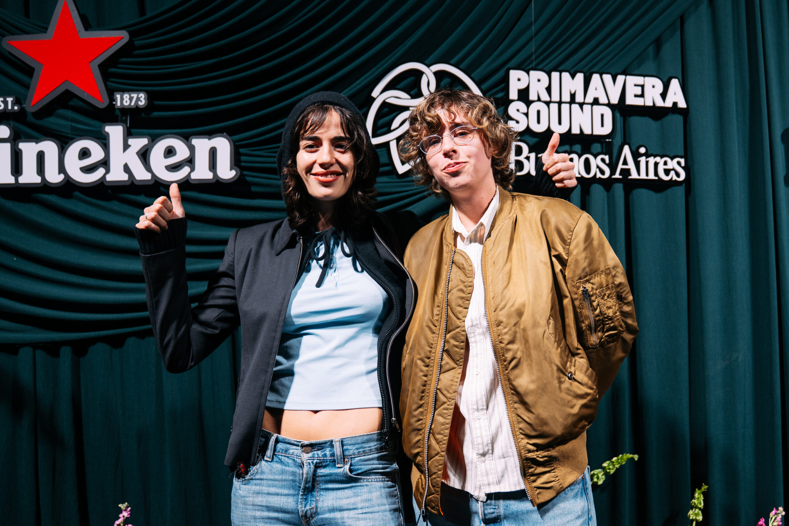 Dos invitados posan ante el backdrop del evento, con los logos de Primavera Sound Buenos Aires y Heineken detrás.